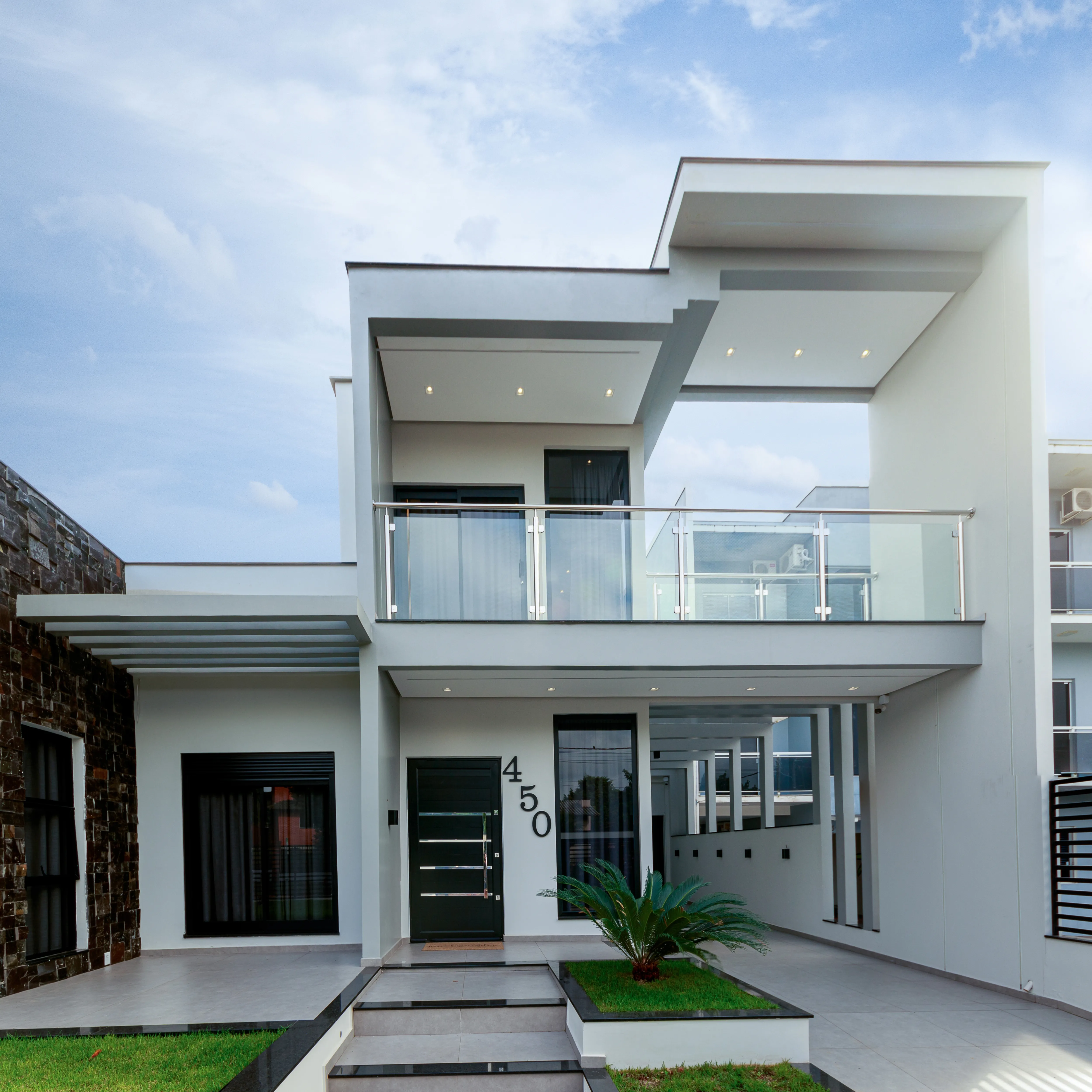 Fachada de uma residência moderna com elementos em pedra escura, grandes janelas de vidro.