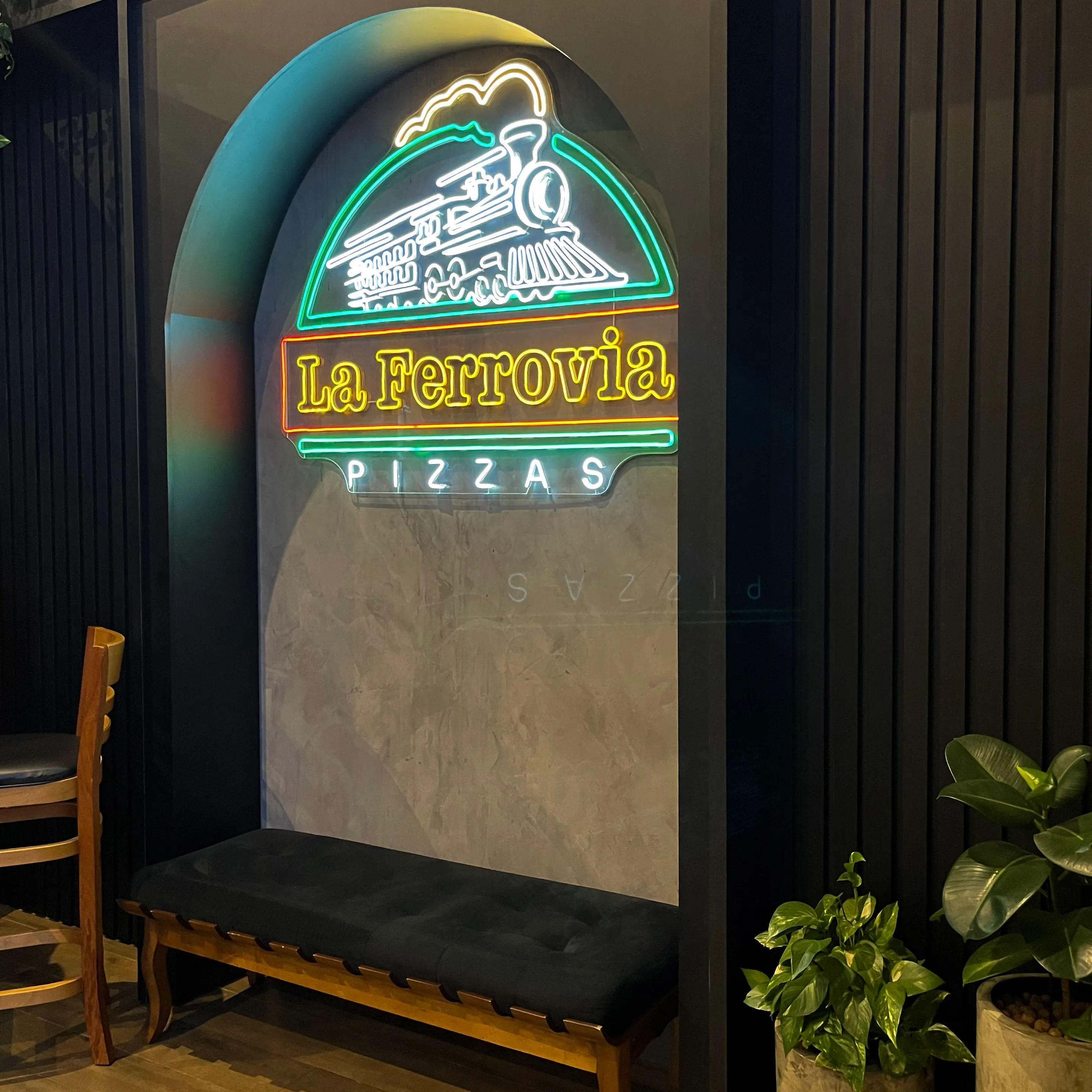 Logo da pizzaria com bancos abaixo, ideal para tirar fotos.